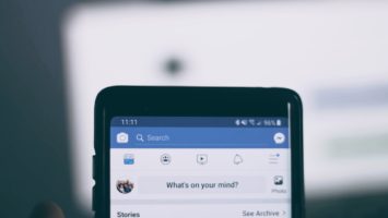 Une personne tenant un smartphone et naviguant sur Facebook