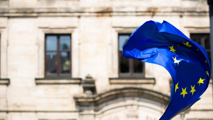 Le drapeau de l'Union européenne (UE) flottant au vent devant un bâtiment.