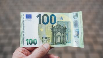 une personne avec un billet de 100 euros en main.