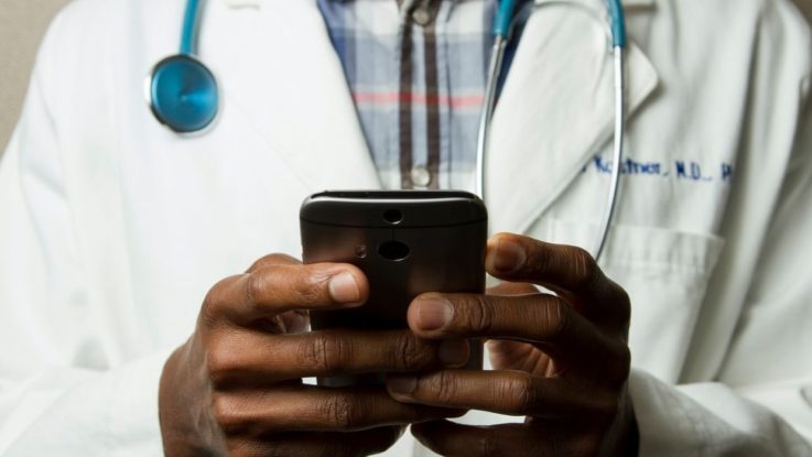 Un docteur africain avec un smartphone en main.
